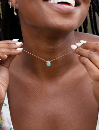 Person wearing a delicate necklace with a green pendant