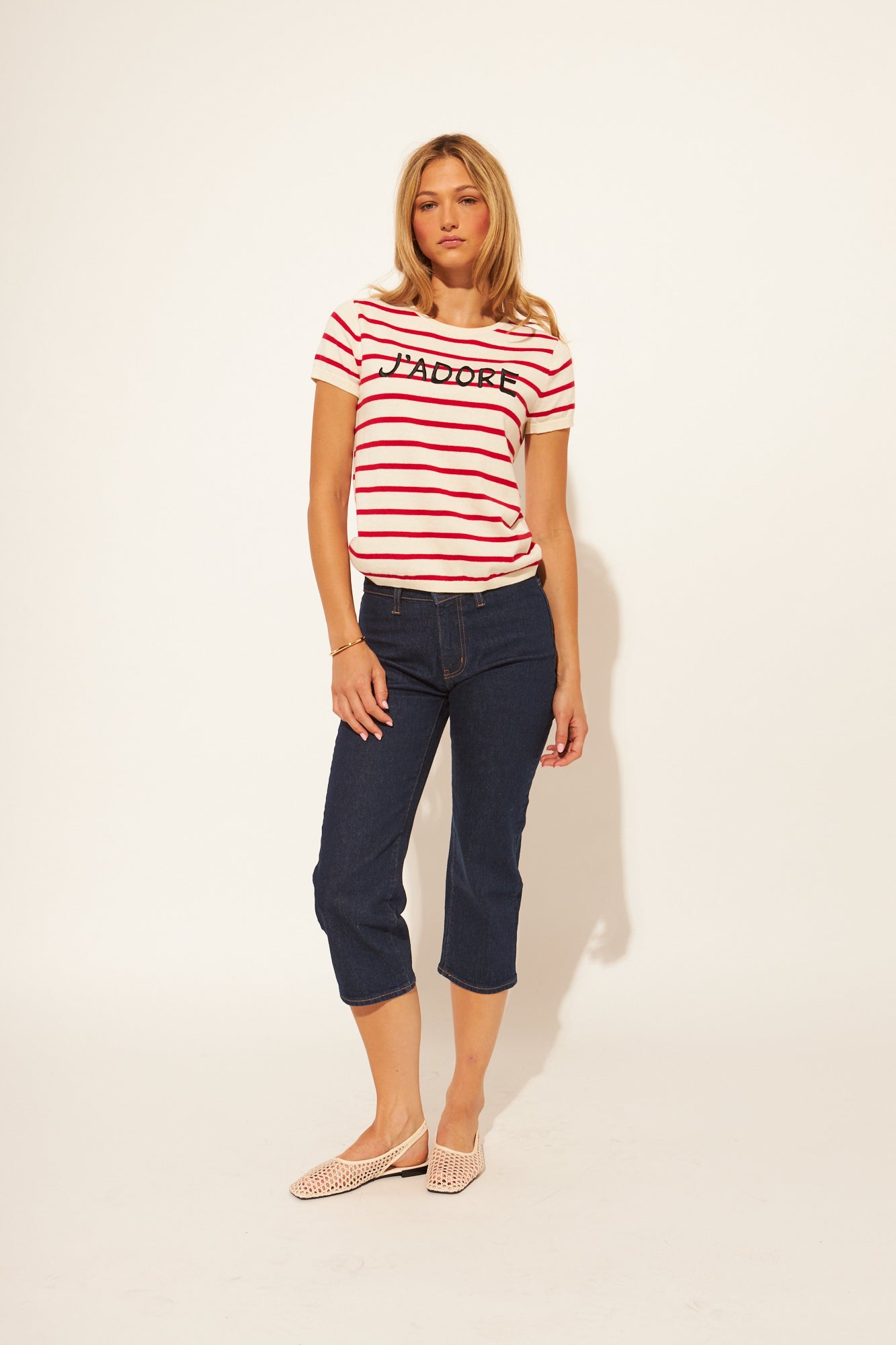 Woman wearing a red and white striped t-shirt and blue jeans on a plain background