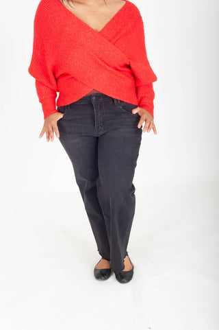 Person wearing a red sweater and black jeans on a white background