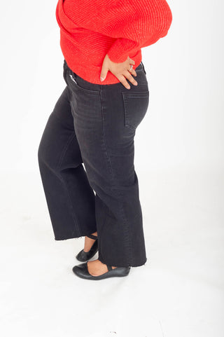 Person wearing black wide-leg jeans and a red sweater on a white background