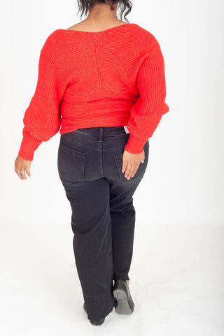 Person wearing a red sweater and dark pants on a white background