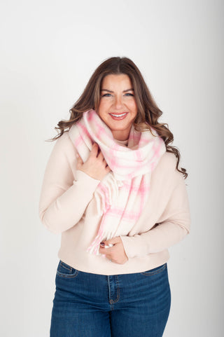 Woman wearing a pink scarf and beige sweater on a white background