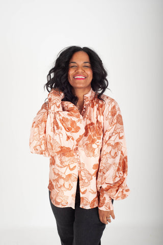 Woman wearing a patterned blouse against a white background
