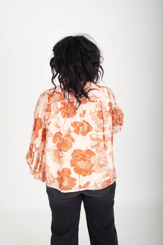 Person wearing an orange floral blouse on a white background