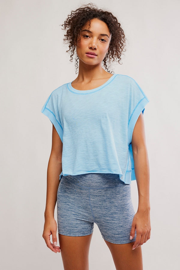 Woman wearing a light blue t-shirt and gray shorts against a plain background