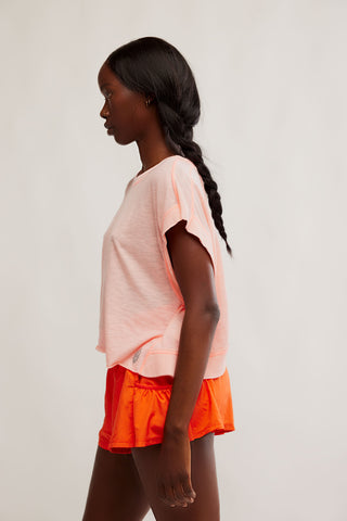 Woman wearing a peach top and orange shorts on a plain background