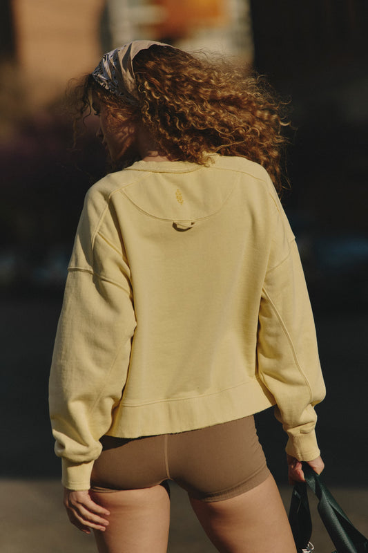 Person wearing a yellow sweatshirt walking outdoors