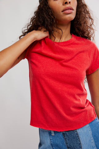 Person wearing a red t-shirt and blue jeans against a plain background