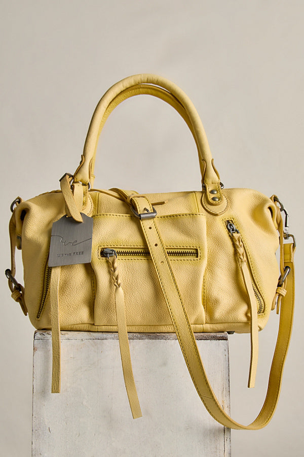 Yellow handbag with a visible brand tag on a light gray background