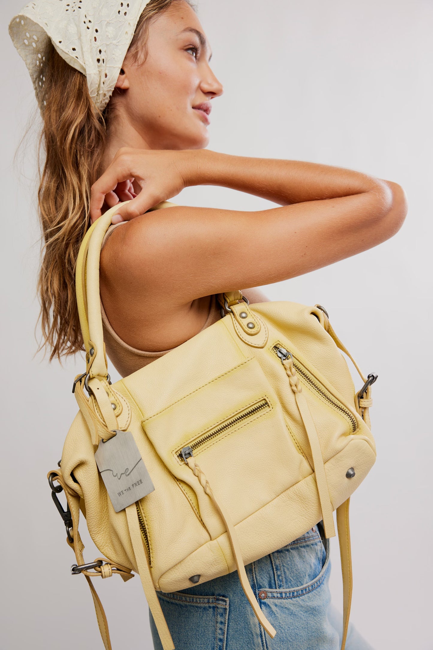 Woman holding a yellow backpack against a plain background