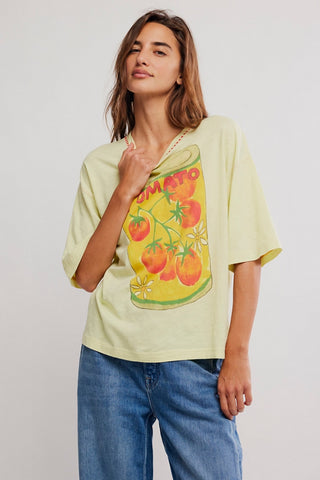 Woman wearing a light green t-shirt with a tomato graphic design on a plain background