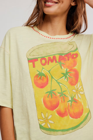 Person wearing a light-colored t-shirt with a tomato-themed graphic design.
