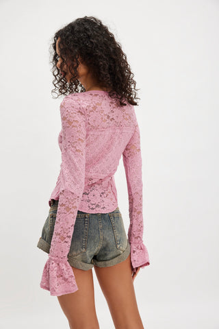 Person wearing a pink lace long-sleeve top and denim shorts on a white background