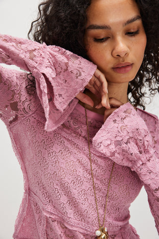 Woman wearing a pink lace dress with a plain background