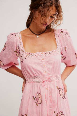 Woman wearing a pink floral dress with a plain background
