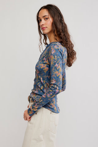 Woman wearing a blue floral long-sleeve shirt against a plain background