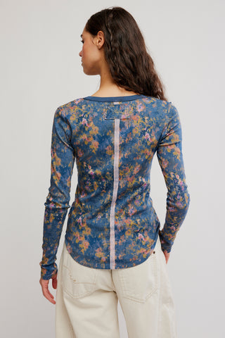 Woman wearing a blue floral long-sleeve top on a plain background
