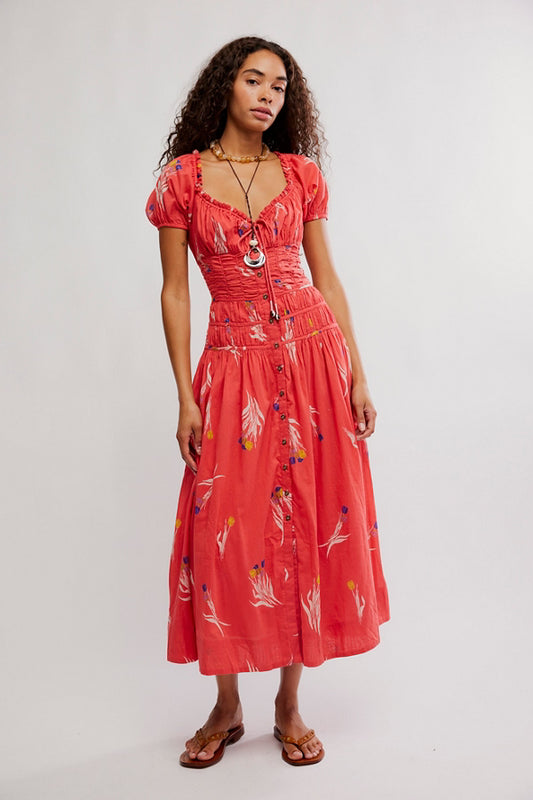 Woman wearing a red dress with floral patterns on a white background