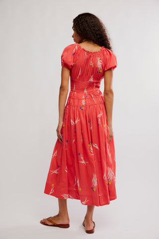 Woman wearing a coral dress with bird pattern on a white background