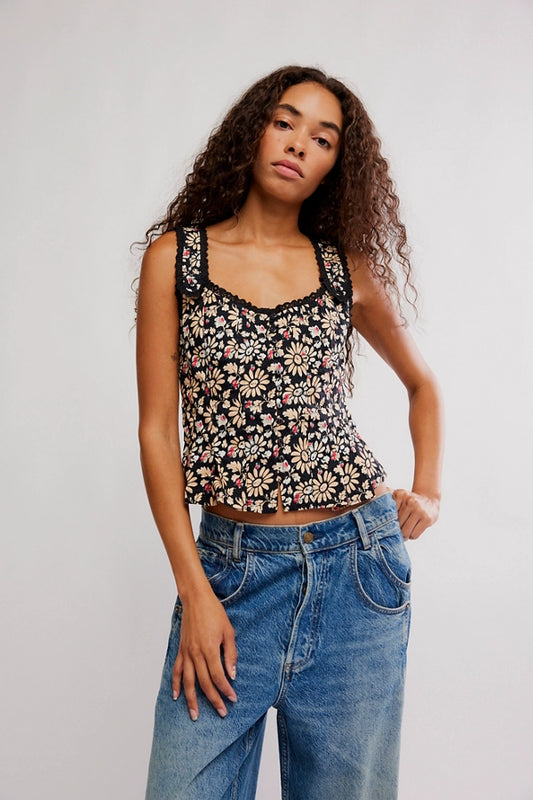 Woman wearing a floral tank top and blue jeans against a plain background
