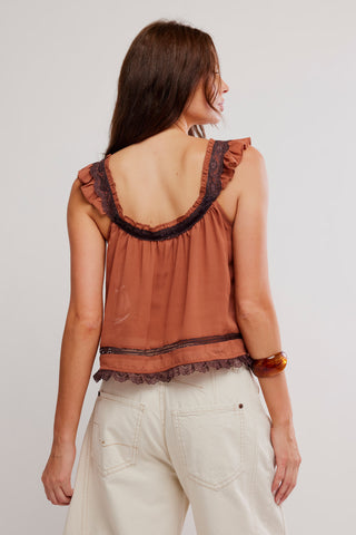 Woman wearing a brown sleeveless top with lace details on a plain background