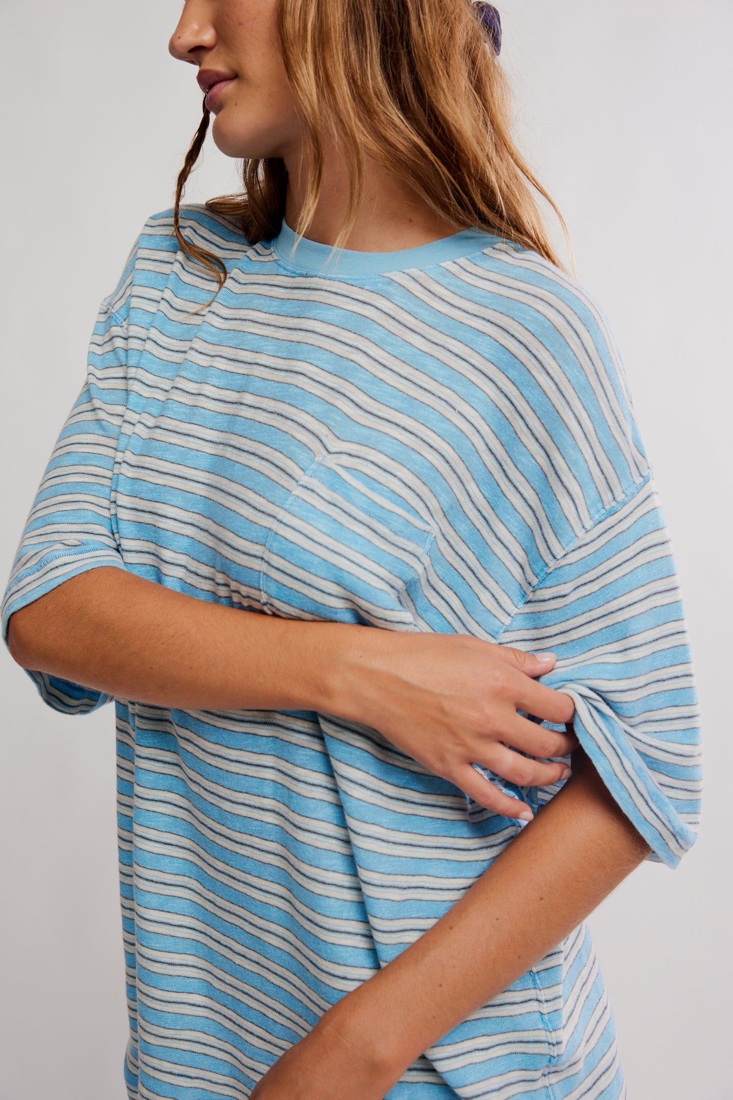 Woman wearing a blue and white striped shirt against a plain background