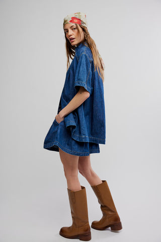 Woman wearing a blue denim dress and brown boots on a white background