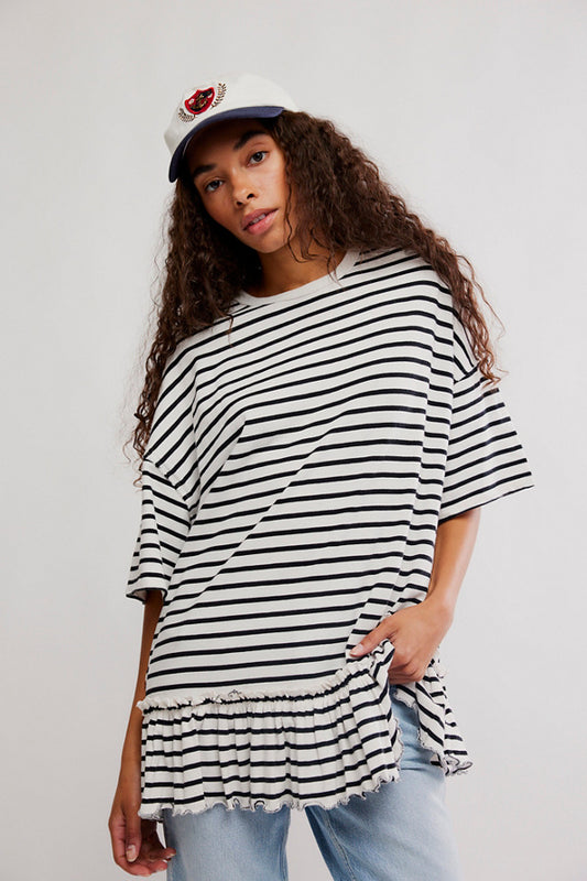 Woman wearing a black and white striped oversized t-shirt with a plain background