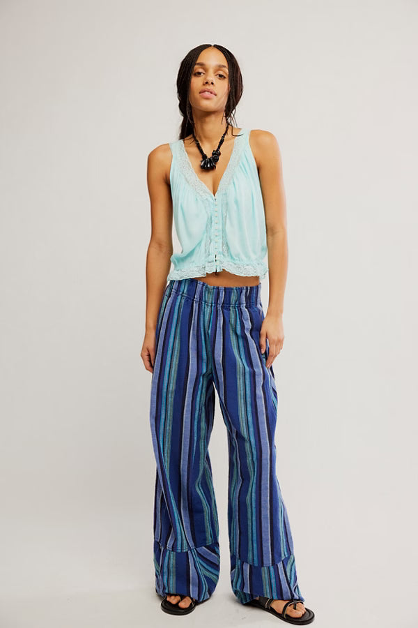 Woman wearing a light blue sleeveless top and blue striped pants on a white background
