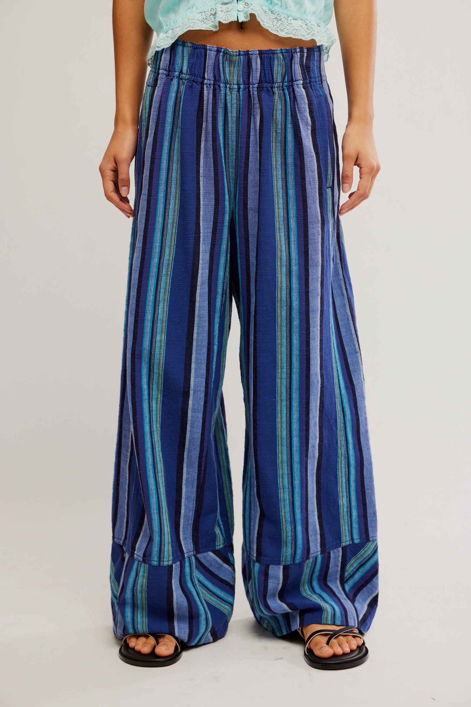 Blue and green striped pants worn by a person on a plain background