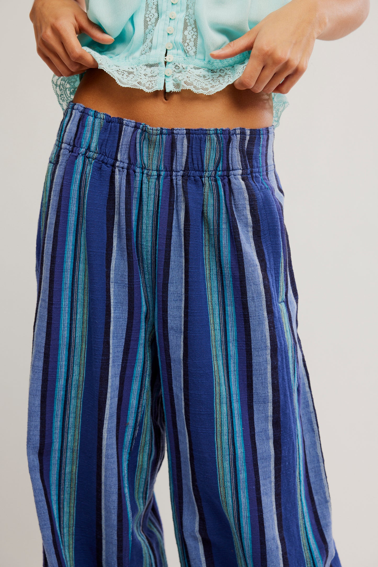 Blue and green striped pants worn by a person on a plain background