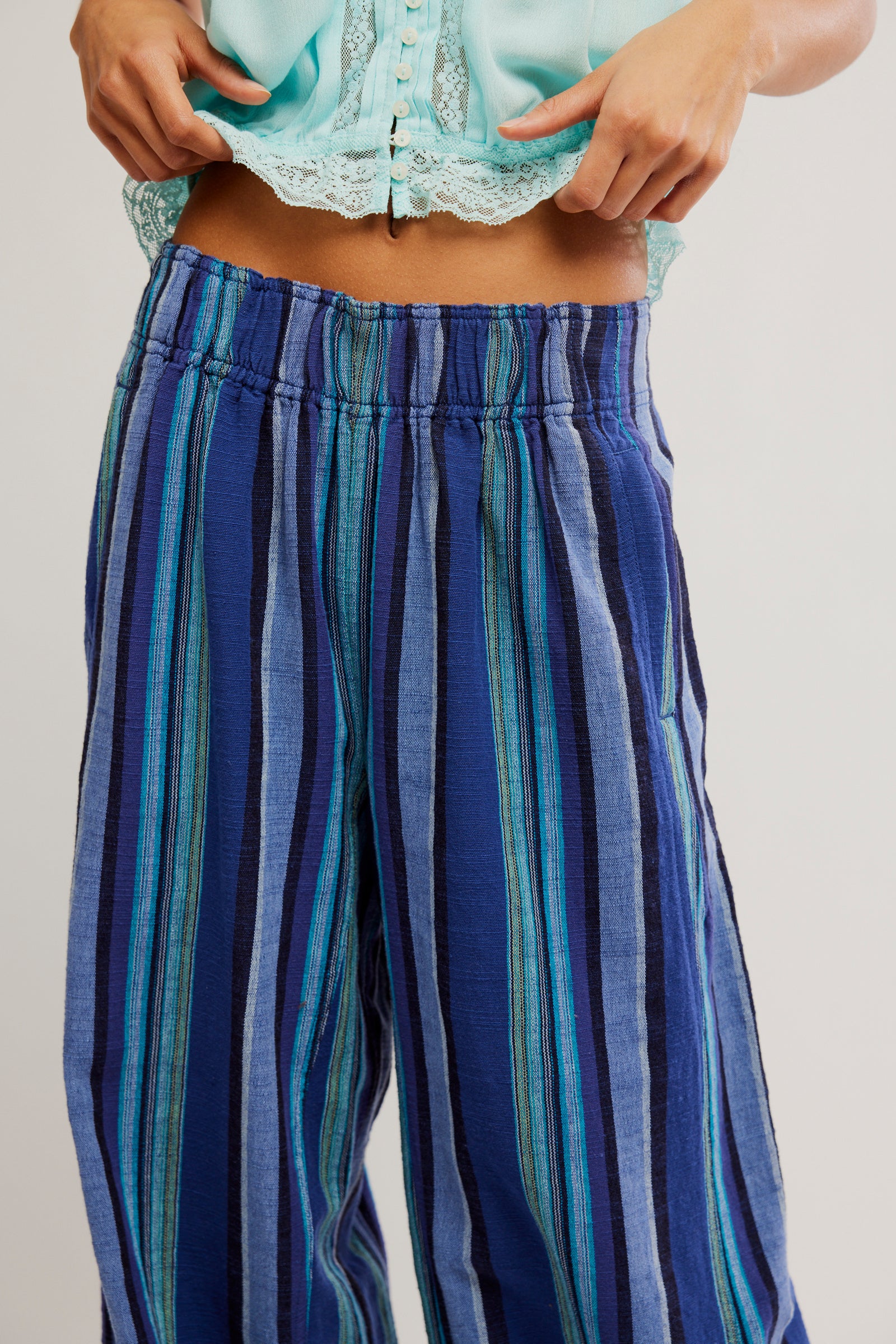 Blue and green striped pants worn by a person on a plain background