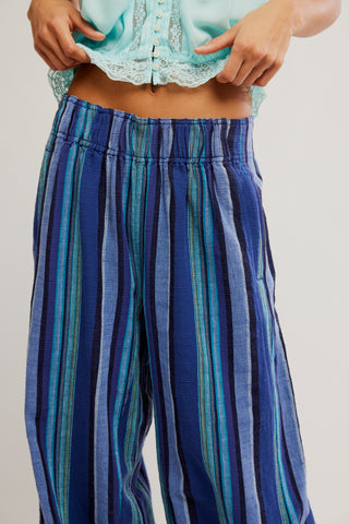 Blue and green striped pants worn by a person on a plain background