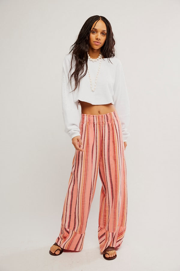 Woman wearing a white top and pink striped pants on a plain background