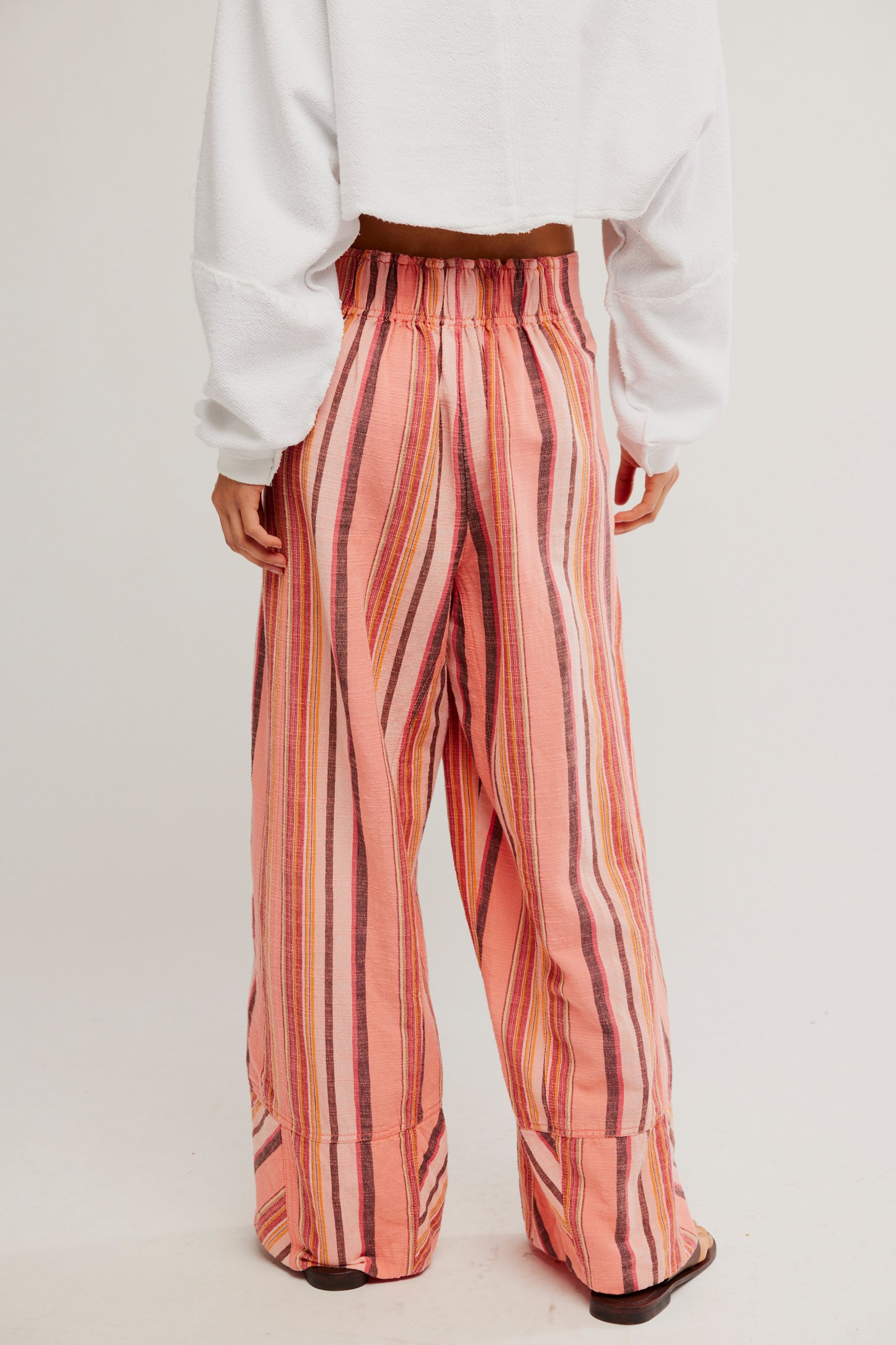 Person wearing pink striped pants with a white top on a light background
