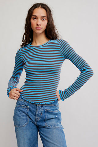 Woman wearing a blue and green striped long-sleeve shirt and jeans on a gray background