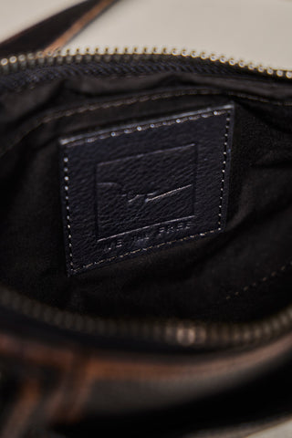 Close-up of the interior of a dark brown leather bag, showing a black stitched patch with an embossed fish logo and the text 'THE FISH SHOP' on the black fabric lining.