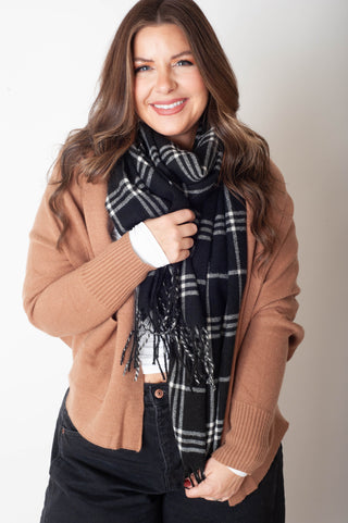 Woman wearing a brown sweater and plaid scarf against a white background