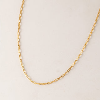 gold chain necklace laying flat on a table.