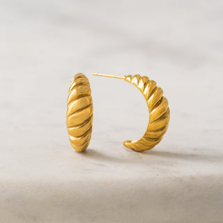 Gold hoop earrings on a light background
