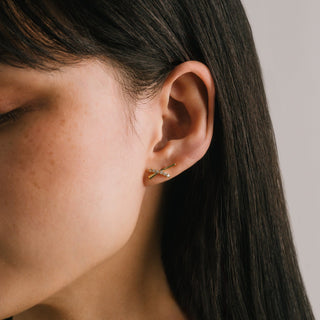 Close-up of a person wearing a gold earring with a neutral background