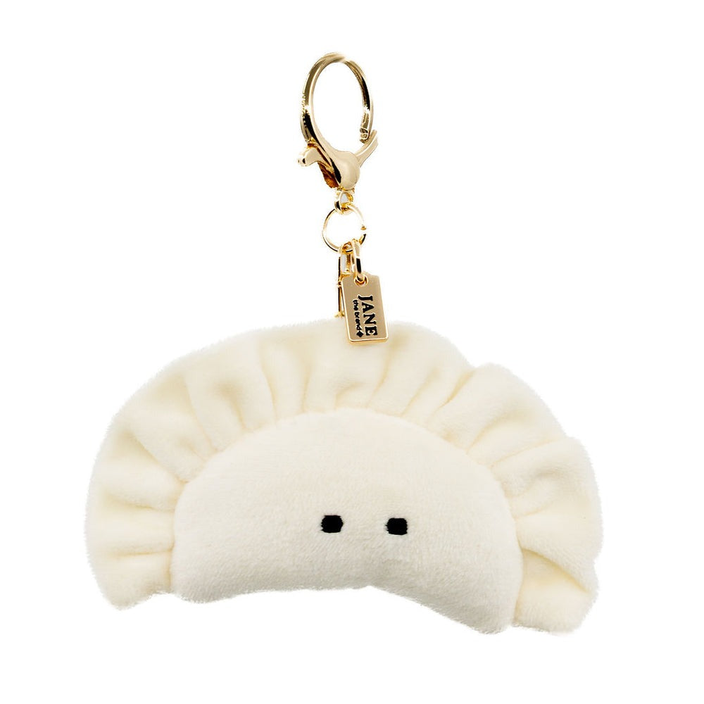 Plush dumpling-shaped keychain with a gold tag on a white background