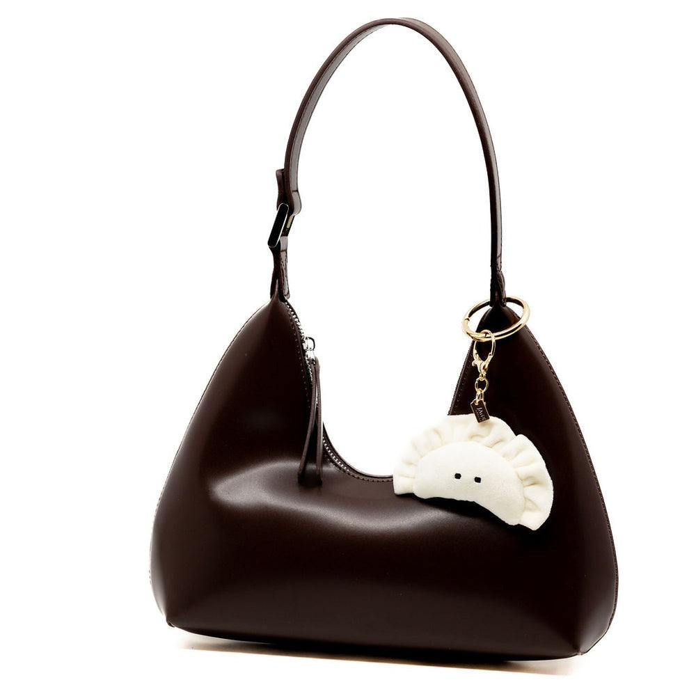 Brown handbag with a white bear keychain on a white background