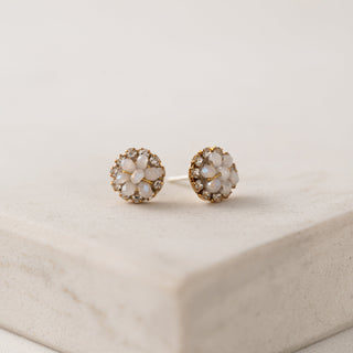 Pair of floral earrings with gemstones on a beige surface
