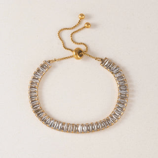 Gold bracelet with clear gemstones on a light background