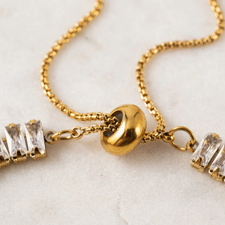 Gold bracelet with clear gemstones on a light background
