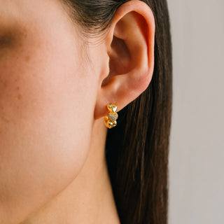 Close-up of an ear wearing a gold earring with a blurred background