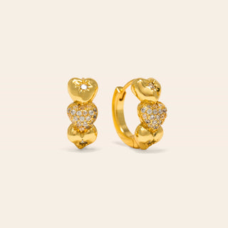 Gold heart-shaped hoop earrings on a beige background