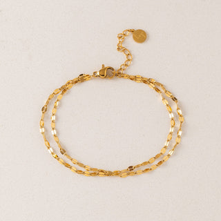 Gold chain bracelet on a light beige background