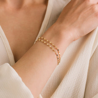 Gold bracelet on a person's wrist with a neutral background